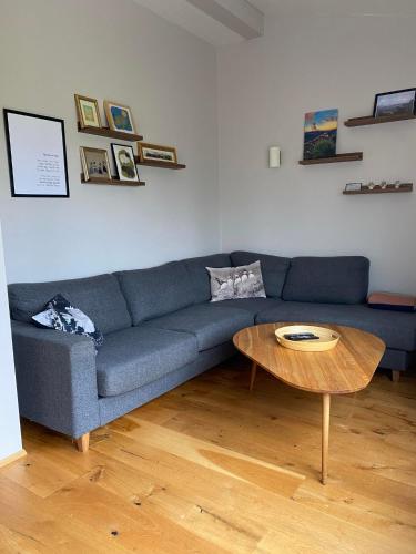 a living room with a blue couch and a wooden table at Norðurhof 5 845 Flúðir with private hot tube in Fludir