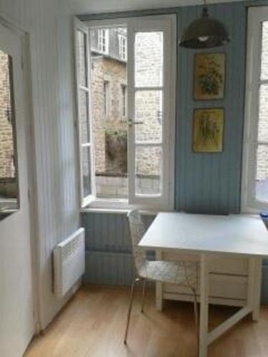 une salle à manger avec une table et deux fenêtres dans l'établissement Le studio de St-Sauveur, à Dinan