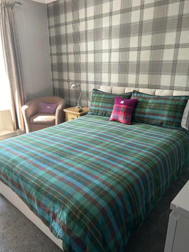 a bedroom with a bed with a green and blue blanket at NC500, Wick Caithness Holiday Home in Wick