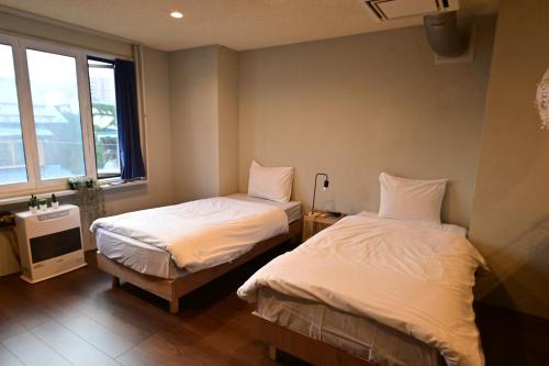 a bedroom with two beds and a window at Tug-B Bar & Hostel in Otaru