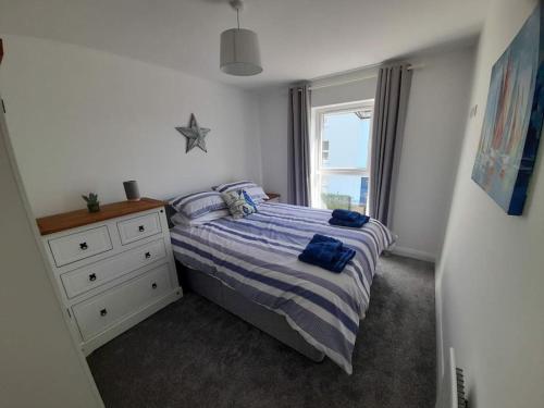 ein Schlafzimmer mit einem Bett mit einer Kommode und einem Fenster in der Unterkunft Rose Cottage Bushmills in Bushmills