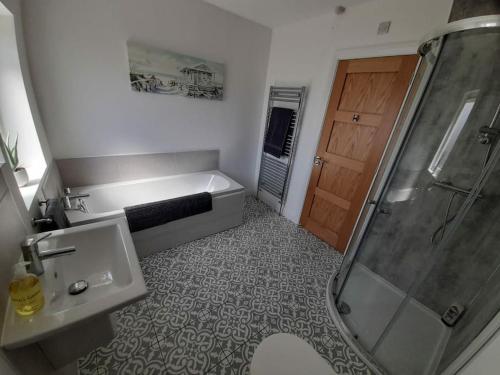 ein Badezimmer mit Badewanne, Waschbecken und Dusche in der Unterkunft Rose Cottage Bushmills in Bushmills