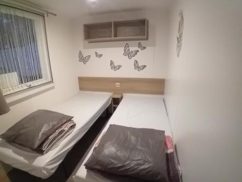 Cette petite chambre comprend 2 lits et des papillons sur le mur. dans l'établissement Mobil home 2 chambres Saint-Jean-de-Monts, à Saint-Jean-de-Monts
