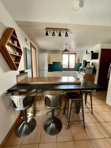 - une cuisine avec une grande table et des tabourets dans l'établissement Maison de charme en bord de mer, à Sainte-Marie-la-Mer