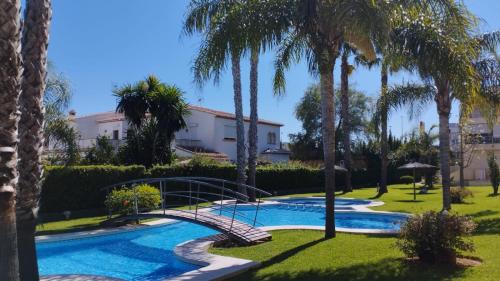 a swimming pool with a bridge and palm trees at Apartamento Familiar Jávea en Planta Baja in Jávea