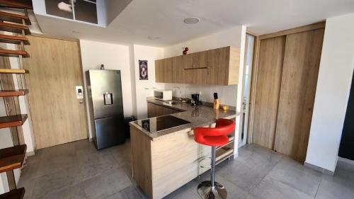 a kitchen with wooden cabinets and a red stool at Apartamentos Borbon Suites in Medellín