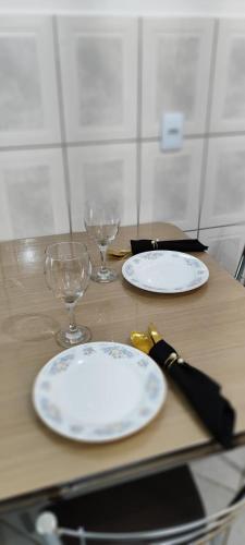 two plates and wine glasses on a wooden table at Morada del Sol Apto Princess in Rio Grande