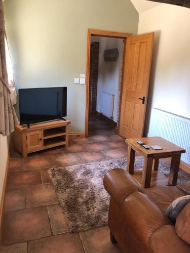a living room with a couch and a flat screen tv at Oak Barn in Wigginton