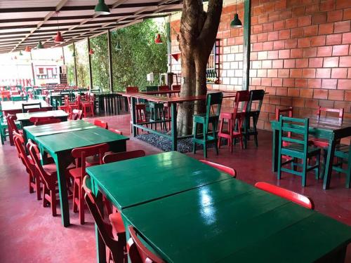 a row of green tables and chairs in a restaurant at Hospedaje San Martin - Finca completa - 18 personas in Pavas