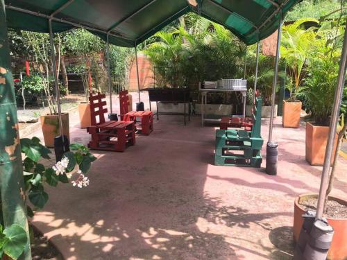 a patio with red and green chairs under a tent at Hospedaje San Martin - Finca completa - 18 personas in Pavas