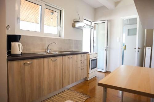 una cucina con mobili in legno, un lavandino e un tavolo di Modern Top Floor Apt, 5min to Acropolis & Plaka ad Atene