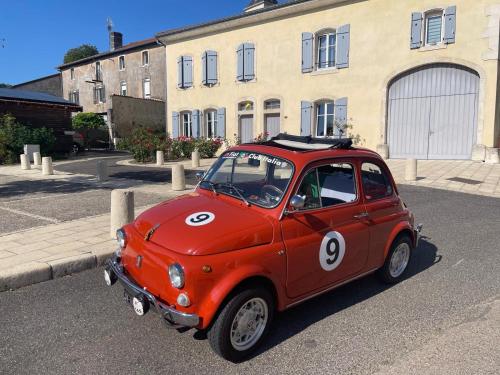 une petite voiture rouge garée devant un bâtiment dans l'établissement Studio 500, à Millery