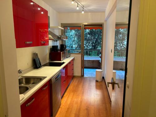 une cuisine avec des armoires rouges et une grande fenêtre dans l'établissement Appartement T2 bord de mer, à Cannes