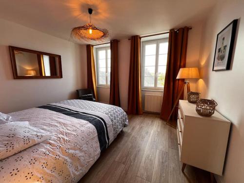 a bedroom with a bed and two windows at Appartement Gordon Smith en plein centre - 2 personnes in Sainte-Mère-Église
