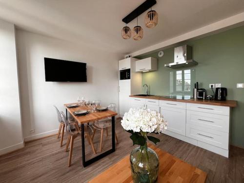a kitchen with a table and a vase of flowers at Appartement Gordon Smith en plein centre - 2 personnes in Sainte-Mère-Église