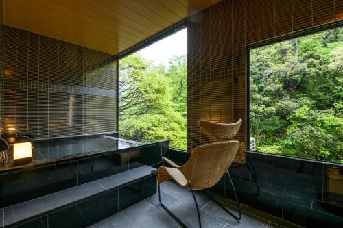 two chairs in a room with a large window at Shirasagiyu Tawaraya in Kaga