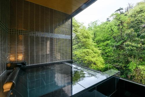 a glass house with a view of the forest at Shirasagiyu Tawaraya in Kaga