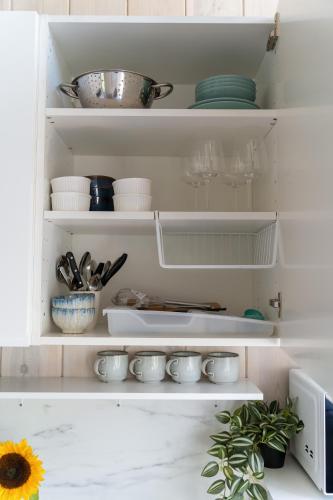 a kitchen with white shelves with dishes and a sunflower at Forrest Guest House Ameli in Ķesterciems