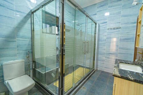 a bathroom with a toilet and a glass shower at Lux Holidays Villa in Kigali