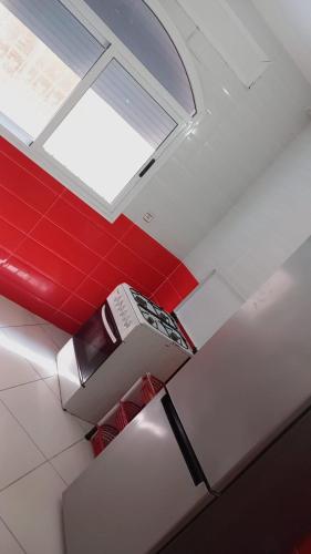 a room with a red wall and a window at Raouia Bk Apartment in Tangier