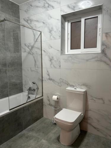 a bathroom with a toilet and a shower and a window at Bella Qawra Maisonette in St. Paul's Bay