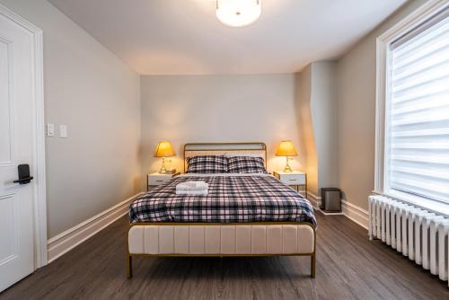a bedroom with a bed with a plaid blanket and two lamps at Atlantic Pub & Hotel in Glen Robertson