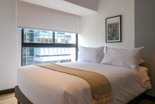 a bedroom with a large white bed with a window at Living 110 Suites by Wynwood House in Lima