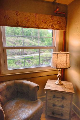 a chair and a lamp in a room with a window at Historic Tapoco Lodge Resort in Tapoco