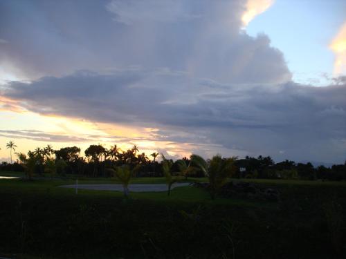 a cloudy sky with palm trees and a road at Tahiti Beach House in Paopao