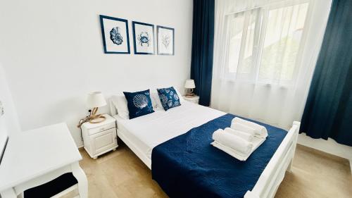 a white bedroom with a blue and white bed and a window at Mirem Boutique Apartments, Central Apartments in Ofrínion