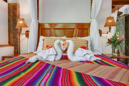 two towel swans are laying on a bed at Ian Anderson Caves Branch Jungle Lodge in Belmopan