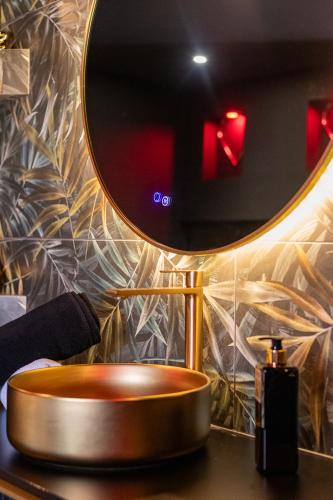 La salle de bains est pourvue d'un miroir rond et d'un lavabo. dans l'établissement Suite D&S Luxury Room, à Firminy