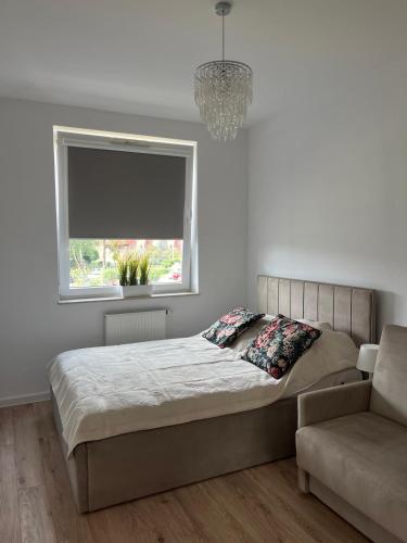 a bedroom with a bed and a window and a chair at BTS Apartaments - Apartamenty Blisko Morza in Gdańsk