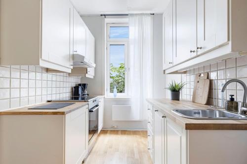 オスロにあるBudget room in the city centreの白いキャビネット、シンク、窓付きのキッチン