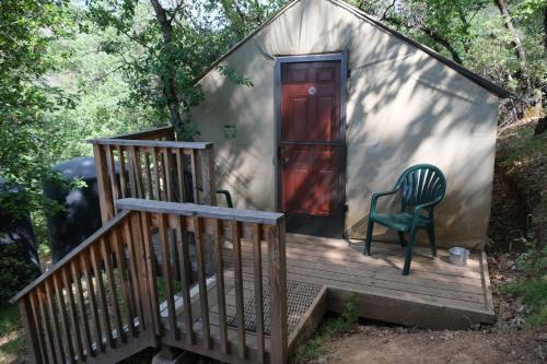 a house with a chair on a wooden porch at Yosemite Bug Rustic Mountain Resort in Midpines