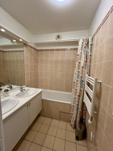 une salle de bain avec un lavabo et une baignoire dans l'établissement Appartement Rénové au Cœur du Quartier Commerçant, à Colombes