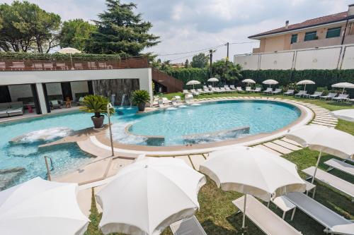 a pool with chairs and umbrellas in front of a building at Hotel Quisisana Terme in Abano Terme