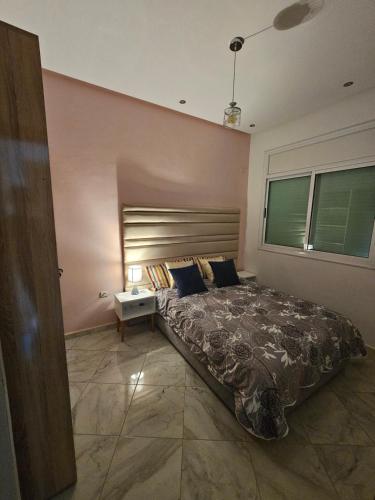 a bedroom with a large bed and a side table at Appartement bien équipé in Kenitra