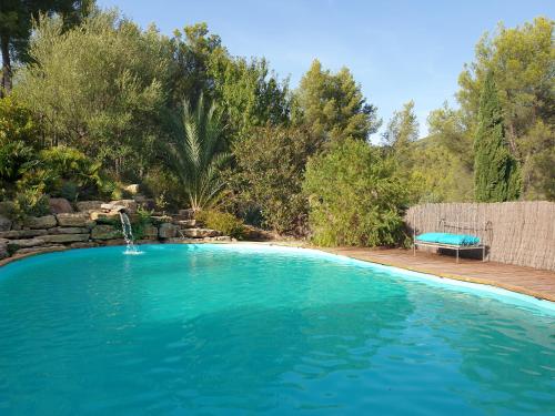 a large swimming pool with a fountain in a yard at Gîte dans Mas provençal ,havre de paix in Le Beausset