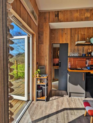 a kitchen with wooden walls and a sliding glass door at Otter Burn Cabin in Oban