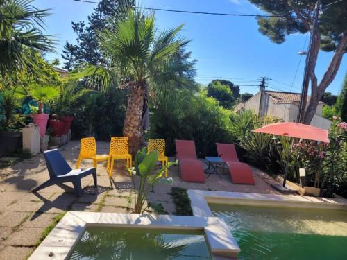 - un groupe de chaises et un parasol à côté de la piscine dans l'établissement Maison de vacances avec piscine et jacuzzi, à Carry-le-Rouet