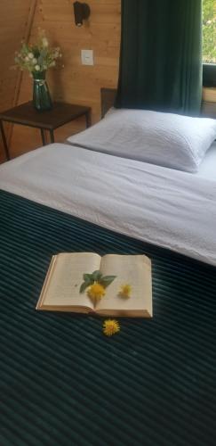 a book with flowers on it on a bed at Emotion Kazbegi in Stepantsminda