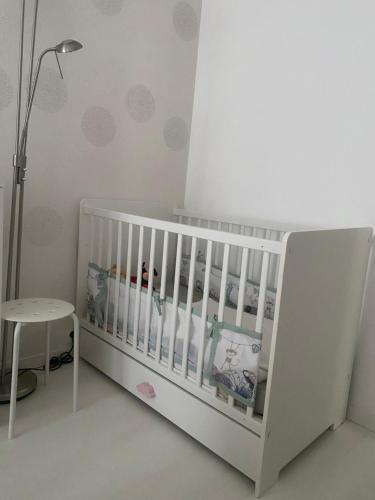 - un lit bébé blanc dans une chambre avec une table dans l'établissement Paris, à Paris