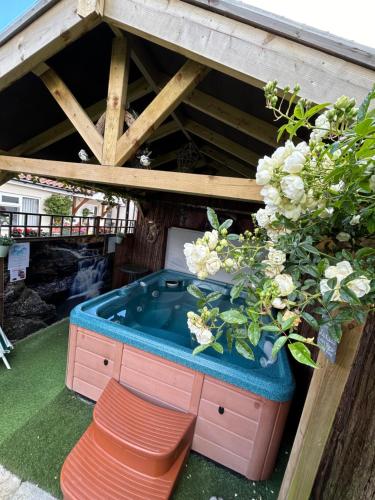 a hot tub sitting under a roof with flowers at Acorn Cottage in Ollerton