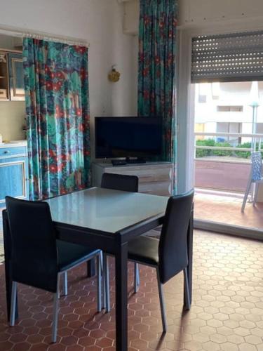 une table à manger avec deux chaises et une télévision dans l'établissement Le Neptune place de Marbre plage et port, à Saint-Cyprien