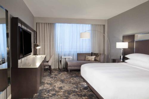 a hotel room with a bed and a desk and a television at Dallas/Fort Worth Airport Marriott in Irving