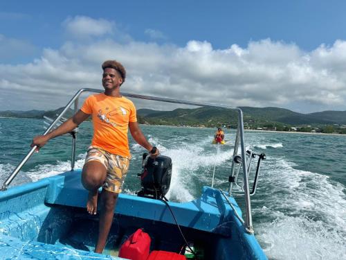 a man sitting on the back of a boat in the water at Buen Hombre Kite School with Accommodations in La Costa de Buen Hombre