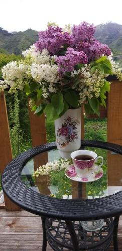 a table with a vase of flowers and a cup of coffee at Emotion Kazbegi in Stepantsminda