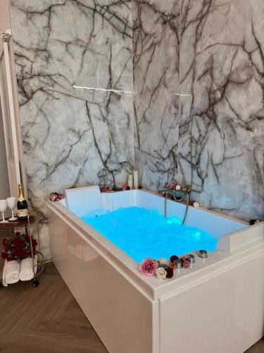 La salle de bains est pourvue d'une baignoire bleue et d'un mur en marbre. dans l'établissement Les chambres d excellence Spa, à Sète
