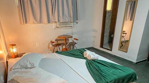 a bedroom with a bed with a green sheet on it at Pousada Mineiro 3 Irmaos in Arraial do Cabo